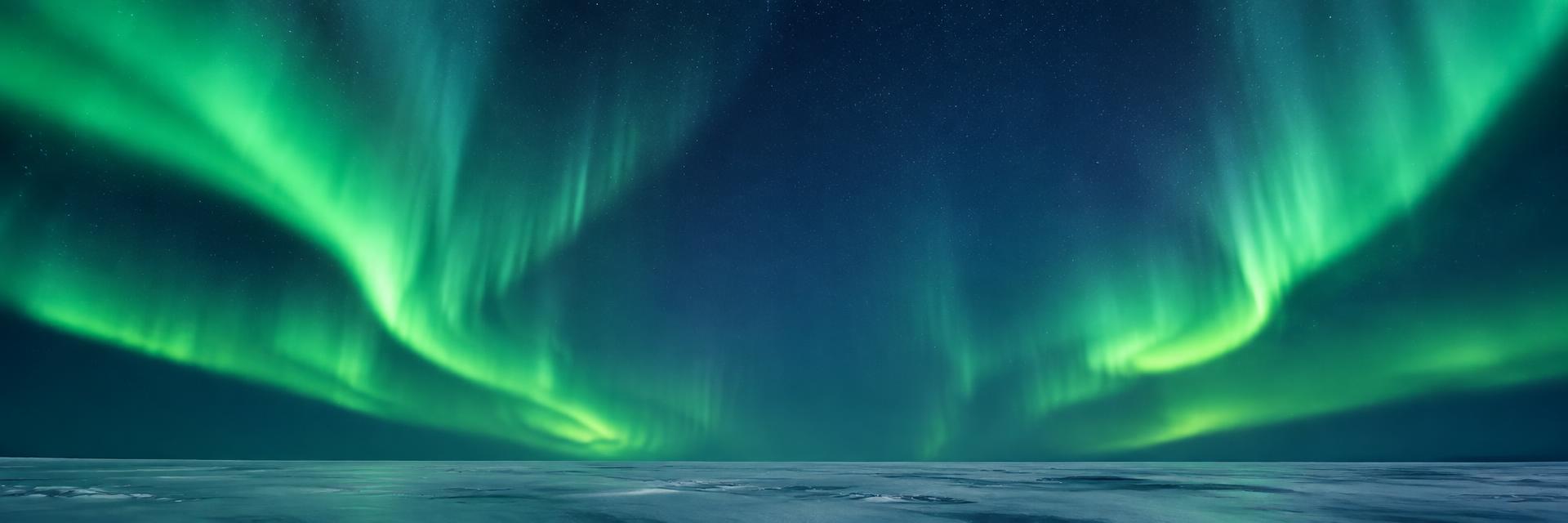 Aurora boreala zeru izartsuan, elurrezko horizonte irekiaren gainean